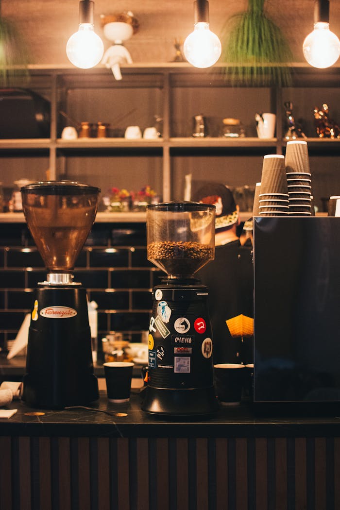 Warm coffee shop scene featuring espresso machines and ambient lighting at a stylish counter.